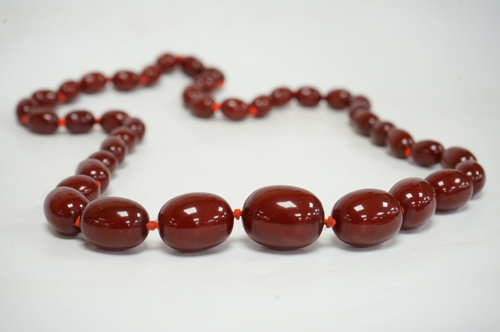 A single strand graduated simulated oval cherry amber bead necklace, 72cm, gross weight 100 grams.